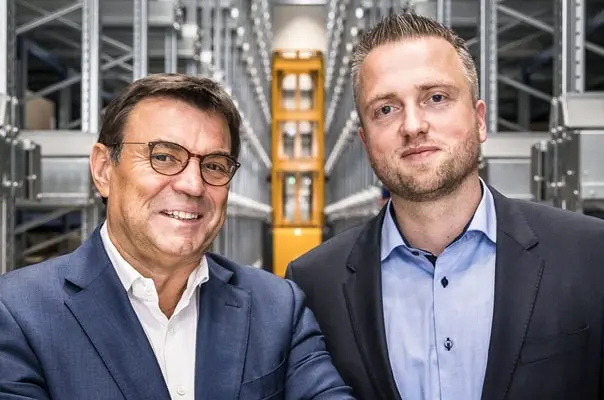 Двама мъже в костюми се усмихват в завод